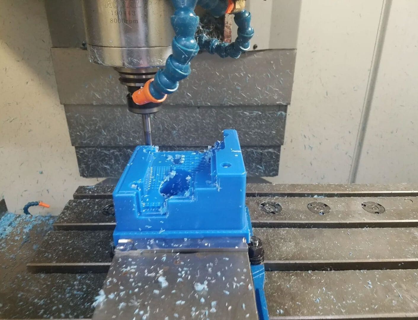 A blue machine is being worked on by an orange drill.
